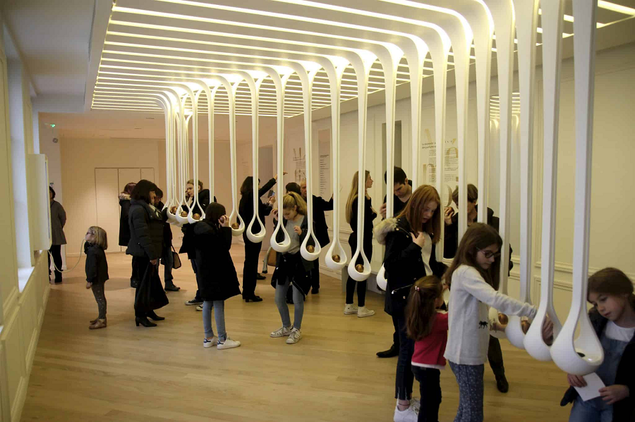 Không gian trưng bày của Scent Drops được thiết kế với những kết cấu màu trắng trải dài từ trần nhà, sử dụng corian, một loại đá nhân tạo có khả năng tạo ra những đường cong mượt mà và mềm mại. Bên trong mỗi chiếc "nôi" bằng corian là một quả cầu bằng đồng thau. Điểm đặc biệt nằm ở phần màu đen lõm xuống giống như nhụy hoa, giúp khuếch đại mùi hương và phát ra âm thanh.