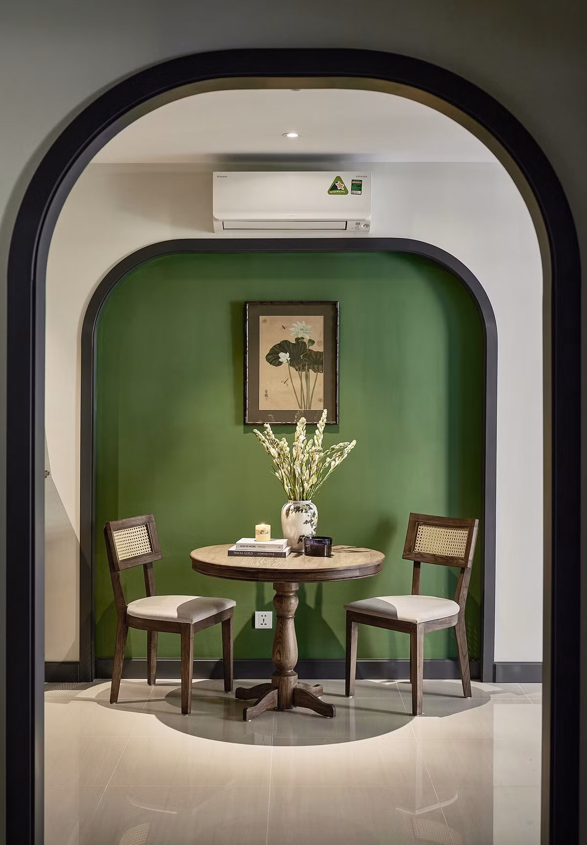 Khu vực bàn ăn, ngăn cách bếp và phòng khách. Phần nội thất chủ yếu sử dụng vật liệu gỗ tự nhiên lau dầu, gỗ công nghiệp chống ẩm sơn PU, gạch nung Bát Tràng, mây tre đan, gạch men rạn terazzo. “Gỗ tần bì làm đồ rời, gỗ sồi làm chi tiết nhỏ và gỗ công nghiệp làm tủ bếp", anh Trung thông tin. Tất cả các loại gỗ tự nhiên sử dụng cho căn hộ được kiến trúc sư sử dụng cách lau màu dầu cao cấp Rubio Monocoat. Sản phẩm chiết xuất từ tinh dầu hạt lanh, sản xuất ở Bỉ theo quy trình công nghệ cao của châu Âu, đạt tiêu chuẩn về độ an toàn cho sức khỏe con người.