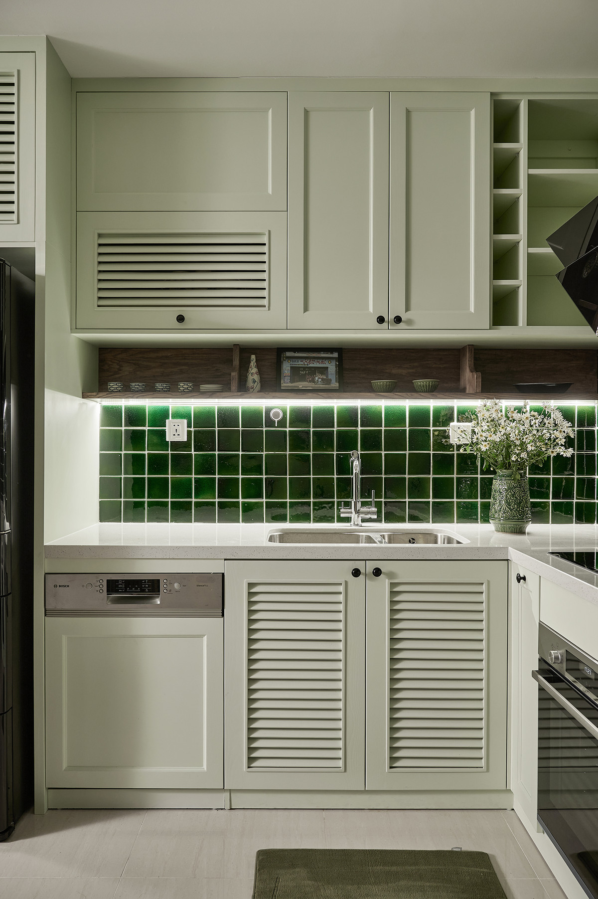 Màu trắng của tủ bếp trung hòa với màu xanh của gạch ốp tường. Ngoài ra, kiến trúc sư còn dùng phương pháp thêm màng ngấm vào gỗ, tạo lớp bảo vệ bề mặt, tăng mức độ sáng bóng mờ và mịn. Cách phủ bóng này tạo cảm giác tự nhiên, sờ thấy vân gỗ, khác hẳn cách sơn phủ truyền thống. Sản phẩm đòi hỏi người thi công phải có hiểu biết và trình độ cao về xử lý gỗ.