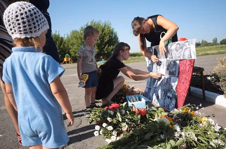 Hai năm sau thảm kịch MH17, người dân Ukraine và thân quyến của 298 nạn nhân xấu số đã tổ chức buổi tưởng niệm dành cho những nạn nhân. Ảnh: Dân làng Petropavlivka, tỉnh Donetsk, miền đông Ukraine đặt những tấm ảnh của các nạn nhân tại khu tưởng niệm tạm thời.