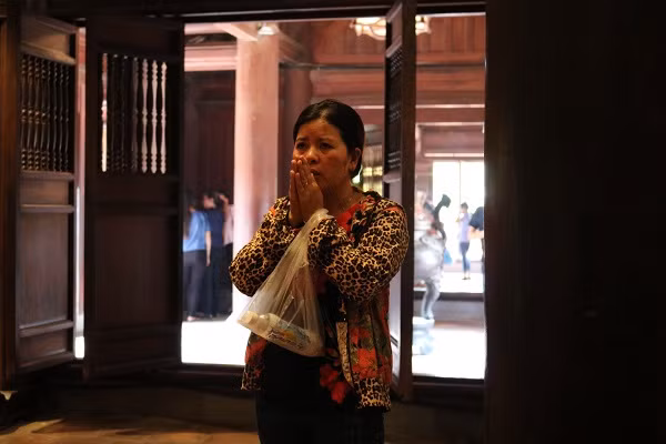 Một phụ huynh từ xa tới Văn Miếu cầu khấn cho con.