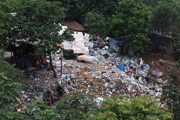 Bãi rác xen kẽ các ngôi nhà trong khu ổ chuột.