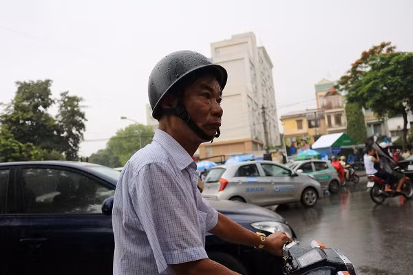 Một vị phụ huynh cố nán lại nhìn theo thí sinh vào cổng dưới trời mưa.