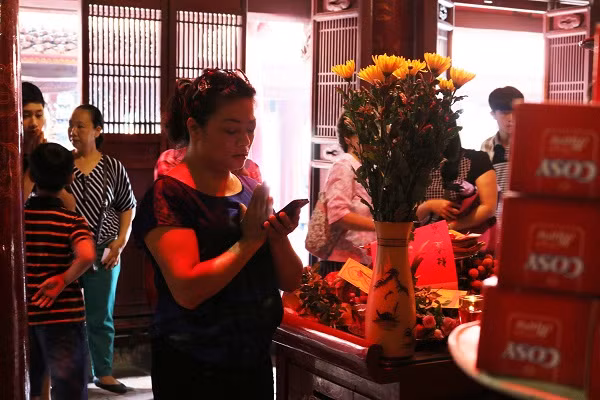 Một phụ huynh đọc bài khấn được lưu trên điện thoại di động.