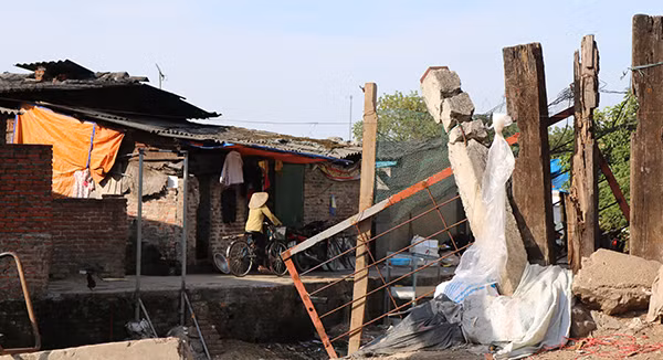 Dãy nhà lụp xụp cạnh cống nước thải được che chắn bằng bạt rách, tấm lợp nhếch nhác.