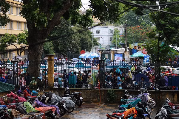 Rất đông các bậc phụ huynh đứng đội mưa đợi con ngoài cổng trường.