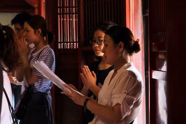 Hai mẹ con cẩn thận đọc theo bài khấn được chuẩn bị trước.