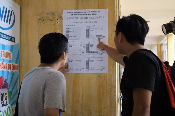 Hai thí sinh chăm chú tìm phòng thi của mình theo chỉ dẫn.