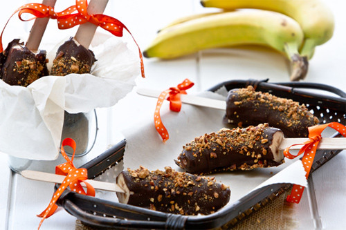 Kem chuối socola. Chuối bóc vỏ, dùng xiên theo chiều dọc quả chuối rồi cho vào ngăn đá. Khi chuối đã cứng lại, bạn đun chảy socola rồi nhúng từng que xiên chuối vào socola, sau đó lăn que kem vào đĩa đựng hạt điều nghiền nhỏ. Ảnh: Internet.