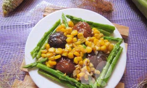 Chần măng tây và nấm bằng nước sôi, sau đó để ra rổ cho ráo nước. Phi hành, tỏi thơm thì cho ngô vào xào cùng chút dầu hào. Ngô gần chín thì cho nấm hương vào xào cùng. Ngô chín hẳn thì cho măng tây vào xào qua. Nêm gia vị vừa ăn rồi tắt bếp. Ảnh: khampha