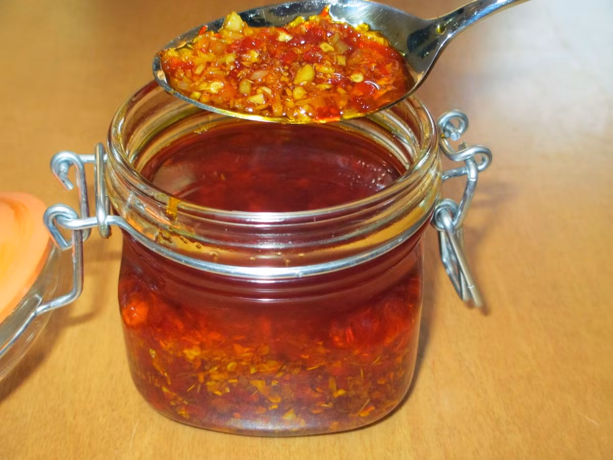 Cuối cùng, cho 2 muỗng canh dầu điều vào, đảo đều thêm 30 giây là được. Tắt bếp, để nguội, cho sa tế ớt tỏi vào hũ thủy tinh, đậy kín nắp và dùng dần. Ảnh: blogspot.com.