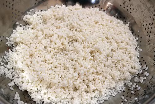 Gạo nếp xay nhặt kỹ bỏ hết hạt thóc và vỏ trấu, cho vào vo thật kỹ cho sạch rồi ngâm nước trong vòng 30 phút. Vớt gạo lên cho róc nước rồi trộn vào gạo nếp ít muối tinh, xóc đều. Sau đó đồ lên như nấu xôi. Ảnh: media