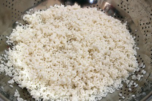 Gạo nếp xay nhặt kỹ bỏ hết hạt thóc và vỏ trấu, cho vào vo thật kỹ cho sạch rồi ngâm nước trong vòng 30 phút. Vớt gạo lên cho róc nước rồi trộn vào gạo nếp ít muối tinh, xóc đều. Sau đó đồ lên như nấu xôi. Ảnh: media