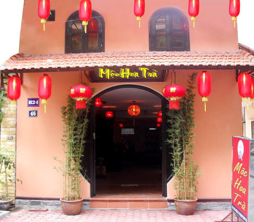 Mộc Hoa Trà. Tọa lạc trên con phố Trấn Vũ yên bình và êm ả, Mộc Hoa Trà nổi bật với thiết kế theo phong cách Trung Hoa hiện đại. Màu trầm là gam màu chủ đạo của quán. Màu nâu của gàn sỗ và vật dụng xung quanh kết màu đỏ vàng của những chiếc đèn lồng tạo nên một Mộc Hoa Trà với dấu ấn của đất nước Trung Hoa cổ xưa. Ảnh: amthuc365