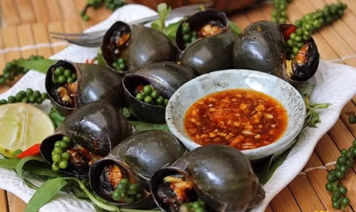 Ốc nướng tiêu xanh vừa là món ăn vặt, vừa là món nhậu được ưa chuộng của người dân nơi đây. Ốc bỏ lên vỉ than nướng, sau khi thấm hơi nóng thì tách lớp mài. Lúc này bỏ tiêu xay (hoặc muối tiêu), đến khi thấy nước ốc sôi là có thể gắp ăn. Trước khi nướng, có thể tẩm ướp sẵn ốc với gia vị giúp món ăn đậm đà hơn. Món này ăn kèm với nước mắm ớt. Ảnh: tourdulichmientay