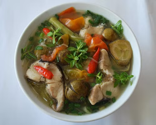 Bắc nồi lên bếp, phi dầu ăn với tỏi cho thơm rồi cho cà chua vào xào cùng. Cà chua chín nhừ thì đổ một bát tô nước vào đun. Khi nước sôi thì cho cá đã ướp gia vị vào đun tiếp. Khi thịt cá chín thì cho sấu đã làm sạch và đập dập vào. Canh sôi lại thì cho hành, ngò rồi bắc xuống và nêm nếm lại cho vừa ăn. Ảnh: baotintuc