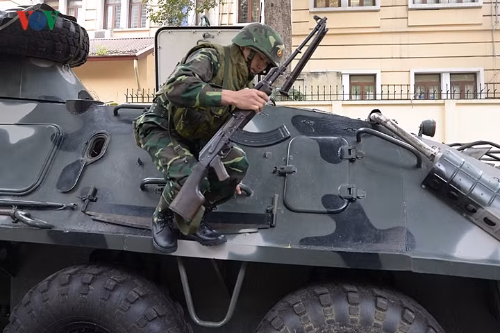 Một quân nhân nhảy từ xe thiết giáp xuống, trên tay là khẩu trung liên RPK.