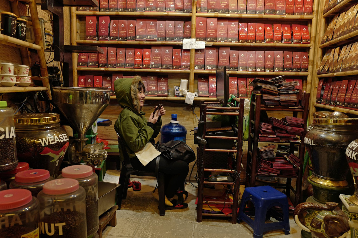 Cô gái ngồi bên trong một cửa hàng bán cà phê xay và cà phê hạt ở Hà Nội.