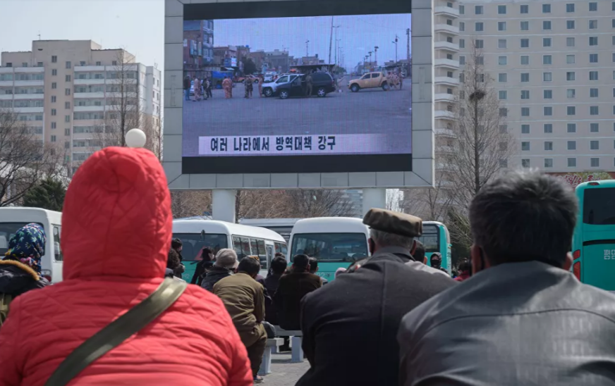 Bản tin liên quan đến tình hình dịch bệnh COVID-19 được chiếu trên màn hình lớn gần nhà ga xe lửa trung tâm ở thủ đô Triều Tiên ngày 1/4.