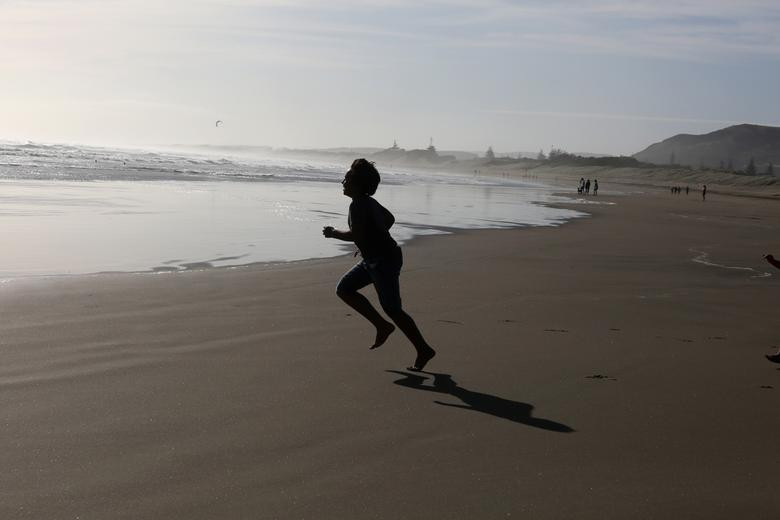 Một em nhỏ chạy trên bãi biển Muriwai gần Auckland hôm 28/4, sau khi New Zealand nới lỏng các biện pháp hạn chế.