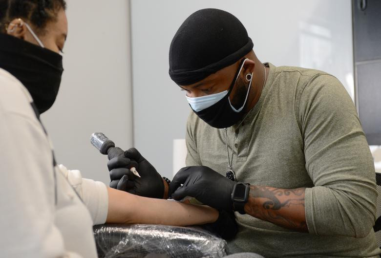 Theo McDaniel đeo khẩu trang cẩn thận khi xăm cho khách hàng tại tiệm Black Ink Atlanta ở Atlanta.