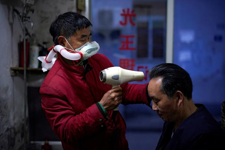 Với việc lệnh phong tỏa được dỡ bỏ, người dân Vũ Hán cũng dần trở về cuộc sống bình thường, song vẫn phải tuân thủ nghiêm biện pháp phòng ngừa lây nhiễm virus SARS-CoV-2. Ảnh: Thợ cắt tóc Yang Guangyu, 54 tuổi, đeo mặt nạ tự chế khi làm việc hôm 11/4.