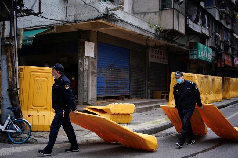 Lực lượng an ninh dỡ bỏ hàng rào trên một con phố tại Vũ Hán. Ảnh: Reuters.