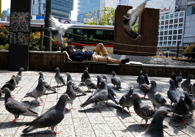 Người đàn ông đeo khẩu trang nằm ngủ trên đường phố vắng vẻ hôm 16/4 sau khi chính phủ Nhật Bản tuyên bố tình trạng khẩn cấp ở thủ đô Tokyo và một số tỉnh.