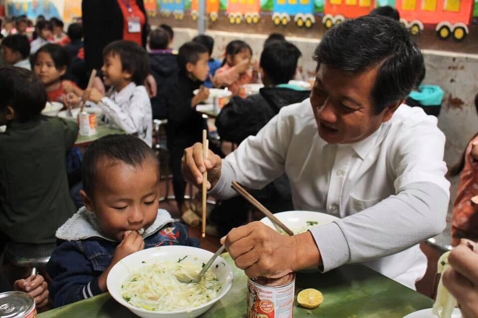 Ông Đoàn Ngọc Hải trìu mến bón phở cho một học sinh.