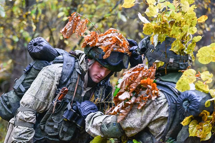 Lính trinh sát dù Nga giúp đồng đội ngụy trang bằng lá cây có sẵn trong rừng. Nguồn ảnh: Bộ Quốc phòng Nga.