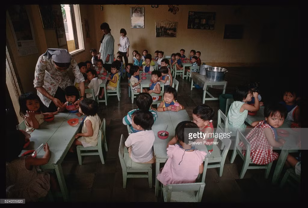 Một ni cô bón thức ăn cho trẻ em tại một lớp học tình thương ở Đà Nẵng, 2/8/1993. Hình ảnh nằm trong loạt ảnh Việt Nam năm 1993 của nhiếp ảnh gia người Mỹ Steve Raymer - phóng viên ảnh kỳ cựu của tạp chí National Geographic.