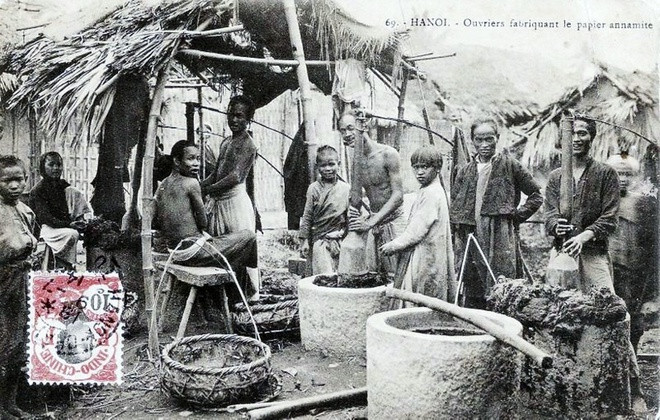 Nghề làm giấy: Trong ảnh chụp cảnh làng làm giấy ở Hà Nội, có thể là làng Bưởi. Những người thợ giã vỏ cây dó trong những chiếc cối đá lớn. Đây là nguyên liệu chính để làm giấy.