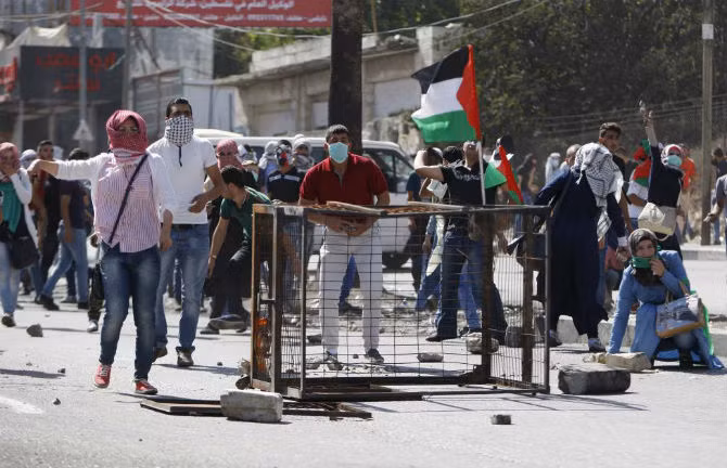 Người biểu tình Palestine ném đá về phía binh sĩ Israel ngày 13/10.