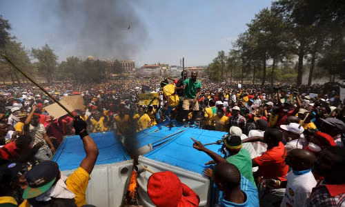 Người biểu tình hô vang khẩu hiệu phản đối tăng học phí trong khi đốt nhà vệ sinh di động ở bên ngoài toà nhà Union, Pretoria ngày 23/10.