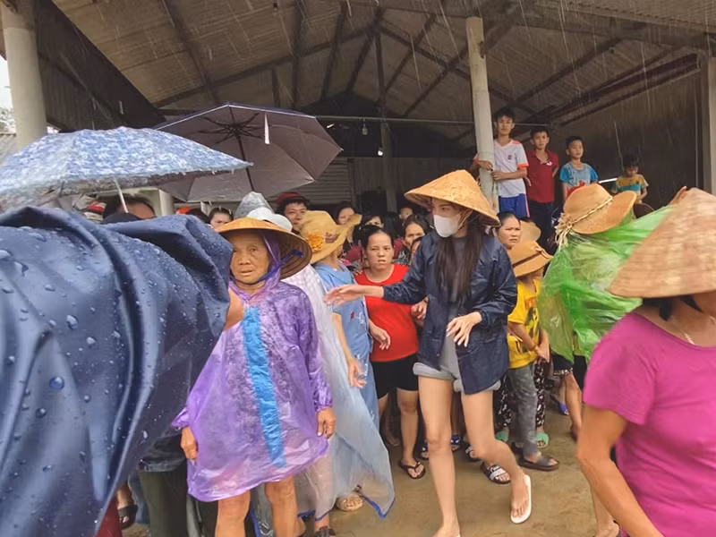 Cô không ngại xắn quần, lội nước để tiếp cận bà con vùng ngập sâu.