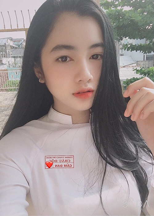 Hình ảnh Cẩm Đan mặc áo dài ngồi trên ghế nhà trường.