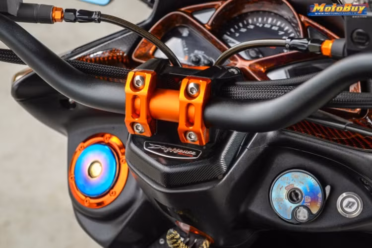 Ngoài mặt đồng hồ, khối động cơ và bộ chuyển động giữ nguyên bản, chiếc SMAX 155 được chủ nhân độ lại gần như toàn bộ với ghi-đông và cùm phanh cũng được thay thế, bổ sung thêm đồng hồ đo điện Koso, móc treo đồ carbon, ốp carbon trên các chi tiết và nắp khóa sơn đổi màu.