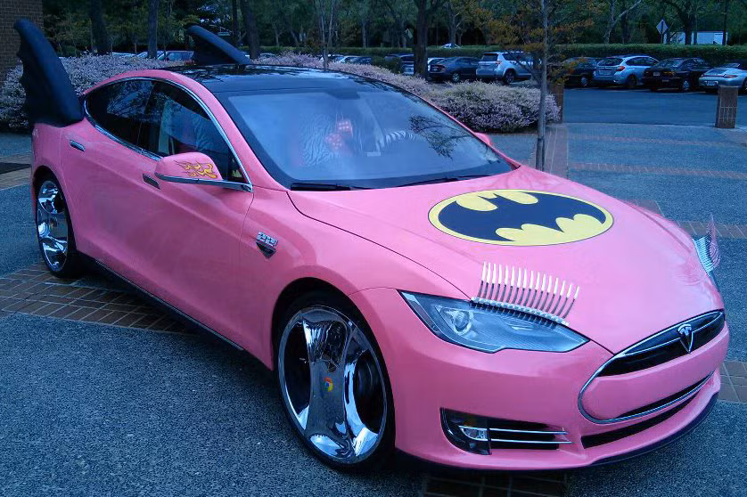 Từ một chiếc xe ôtô điện Tesla Model S nguyên bản, chủ nhân thay đổi diện mạo bên ngoài của xe bằng lớp sơn ngoại thất màu hồng quyến rũ. Tiếp đến là một cặp lông mi màu bạc dài gắn trên cụm đèn pha phía trước, và logo “Người dơi” màu đen trên nắp ca-pô.