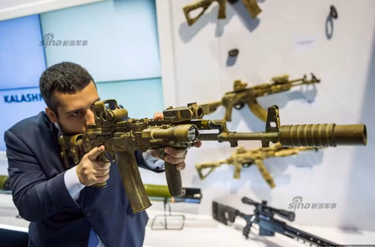 Một vị khách đang ngắm nghía thử khẩu súng trường tiến công AK-74 đã được nâng cấp lắp thêm nhiều phụ kiện như kính ngắm, ống giảm thanh, đèn pin…