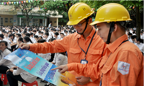 Tuyên truyền viên Công ty Điện lực Ba Đình phát tờ rơi, dán poster tuyên truyền tiết kiệm điện tại trường THPT Phạm Hồng Thái - Ảnh: Hoa Việt Cường.