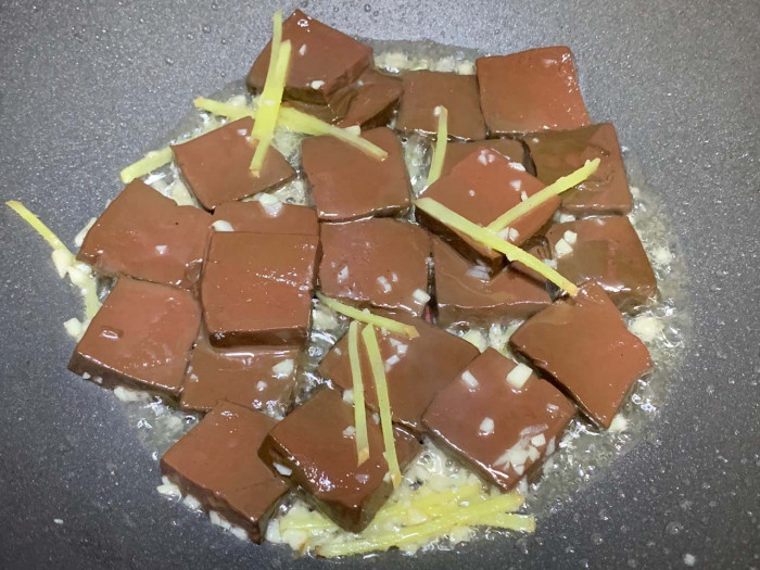 Phi thơm gừng tỏi, cho tiết heo vào xào trong 1 phút. Cho gia vị vào, đảo đều.