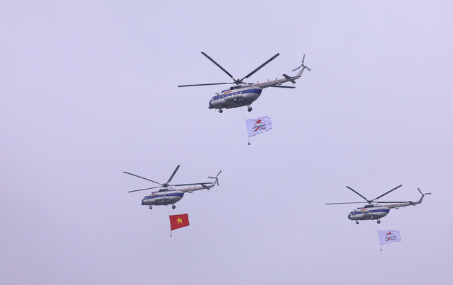Biên đội trực thăng dòng Mi thuộc Trung đoàn không quân 916 cùng cờ Tổ quốc và cờ hiệu Triển lãm Quân sự quốc tế Việt Nam 2022 biểu diễn trên không gian triển lãm. Ảnh: Văn Điệp - TTXVN