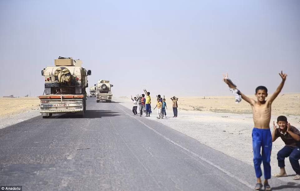 Một bé trai vẫy tay khi đoàn xe quân sự của người Kurd rầm rập thẳng hướng Mosul. Nằm ở bờ tây sông Tigris và cách Baghdad 250 dặm, Mosul từng là nhà của 2,5 triệu người.