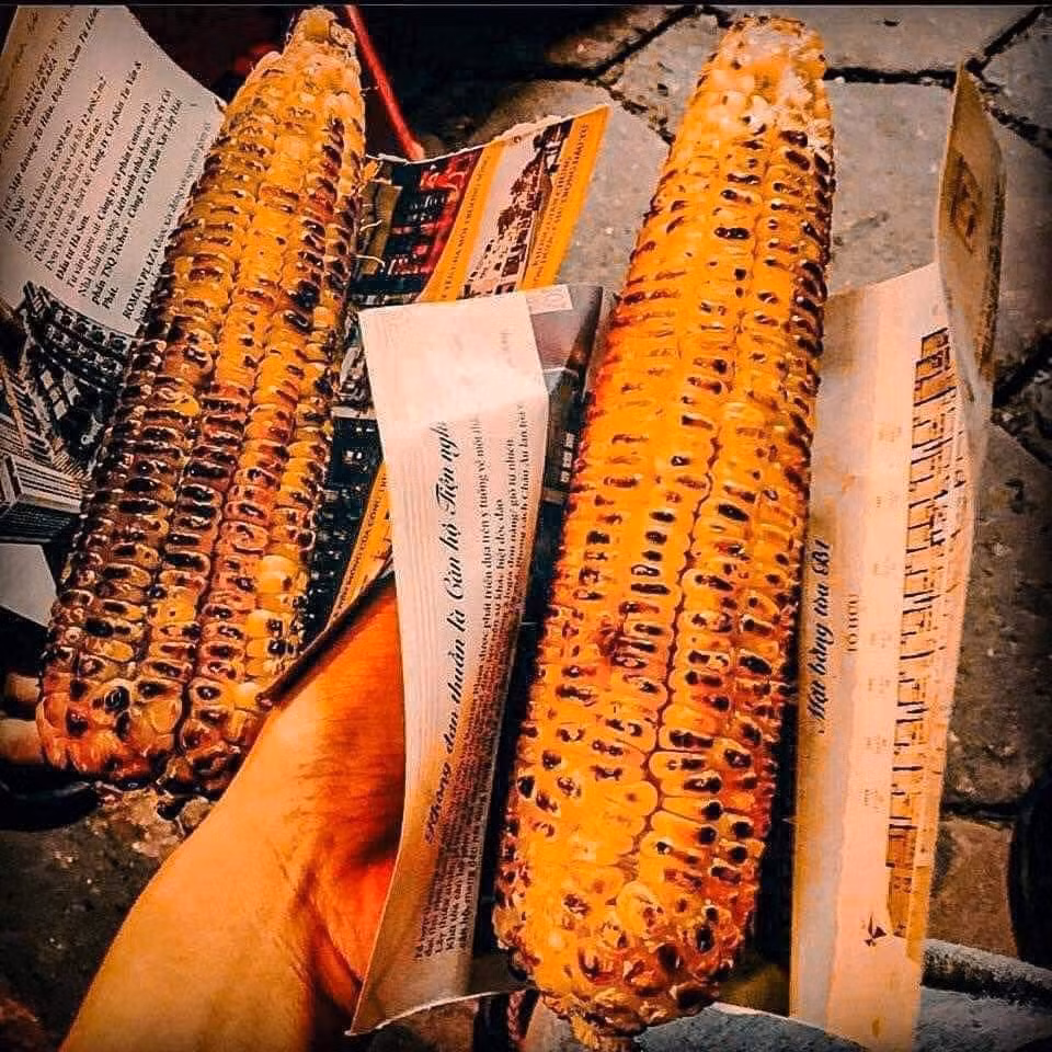 Hà Nội mùa đông, ngõ ngách nào cũng rực lửa. Những bếp than hồng bập bùng, tỏa ra mùi thơm nồng nàn của ngô khoai nướng, vẽ nên một bức tranh đường phố ấm áp. Dọc các tuyến phố Tây Sơn, Tôn Thất Tùng, Nguyễn Lương Bằng, hình ảnh những gánh hàng rong giản dị với ngô khoai nướng nghi ngút khói trở nên quen thuộc.