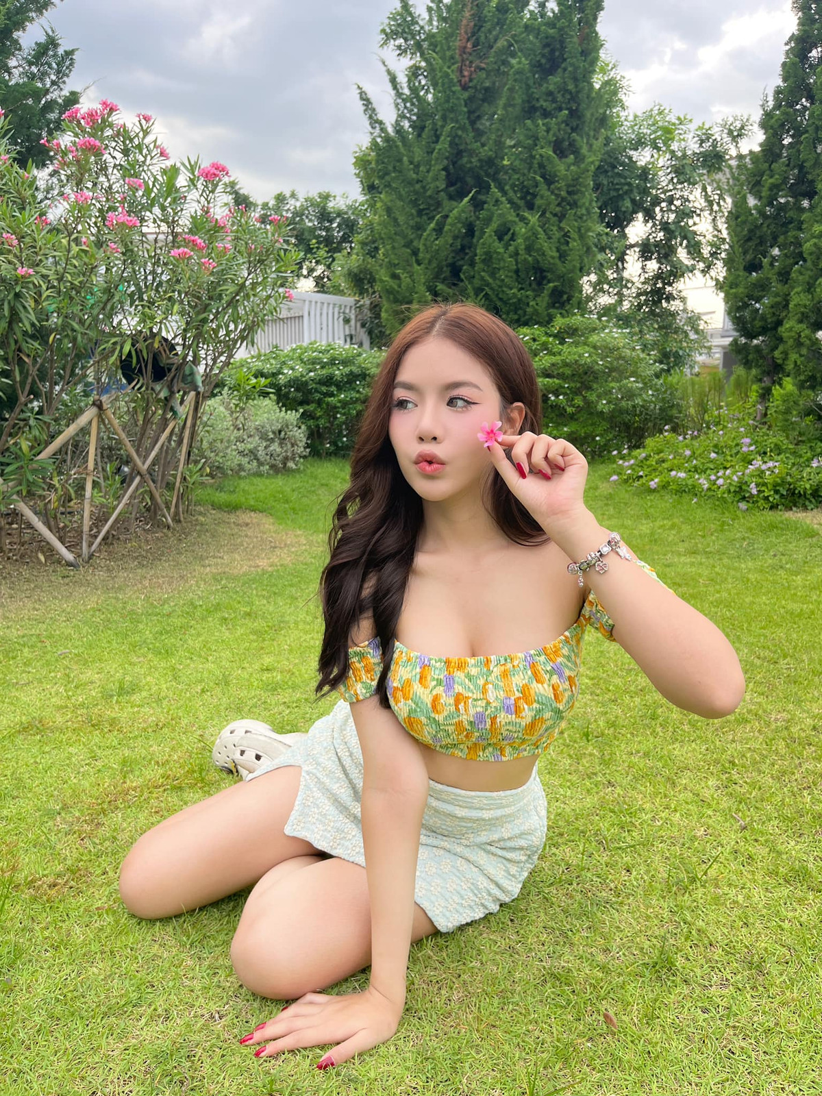 Diện váy trễ vai với họa tiết hoa lá có phần sặc sỡ, kết hợp cùng chân váy ngắn màu xanh nhạt, cô nàng trông vô cùng tinh nghịch, đáng yêu.