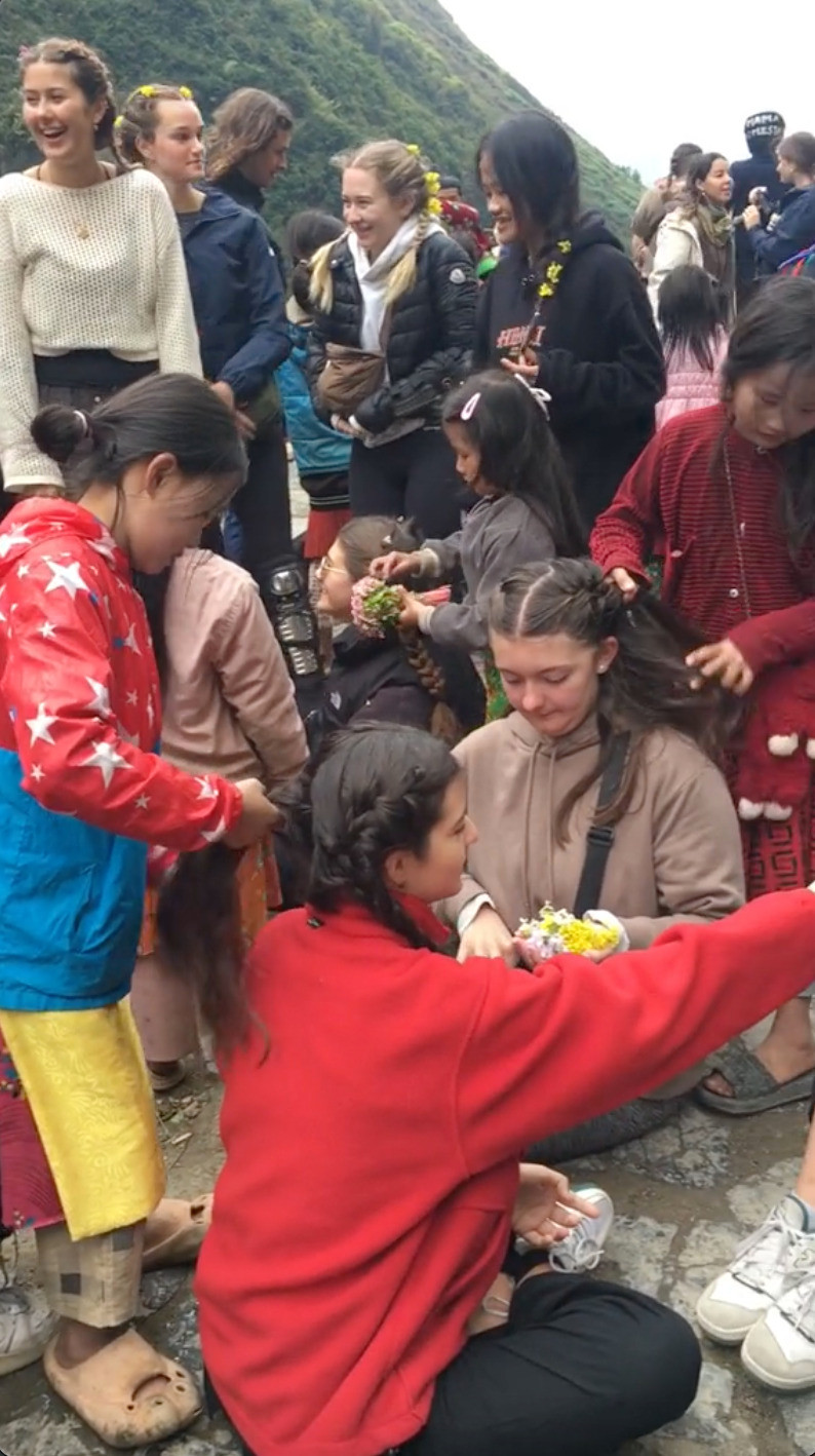 Trong clip, các em tết tóc cho các vị khách Tây và còn cài lên những bông hoa cải vàng - một "đặc sản" mùa hoa của Hà Giang. (Ảnh: hieu.nong.ctv)