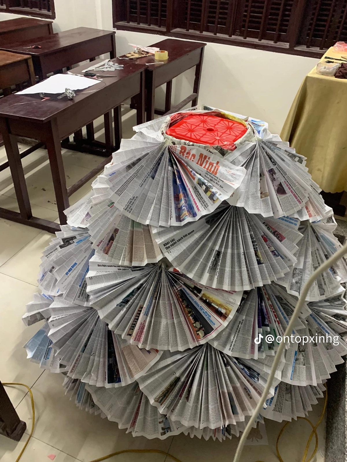 Những tờ báo được gấp lại hình chiếc quạt rồi tỉ mỉ đính lên thân váy.