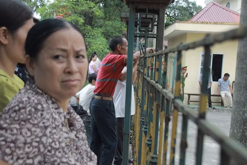 Nhiều người đứng từ phía ngoài để ngóng vào trong, theo dõi diễn biến phiên tòa.