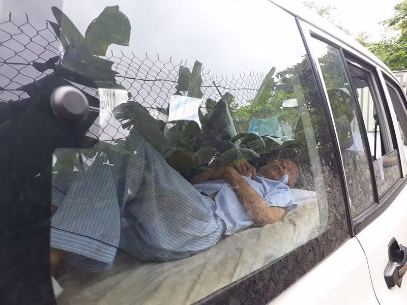 Bị cáo Hùng nằm trên cáng, tỏ ra mệt mỏi.