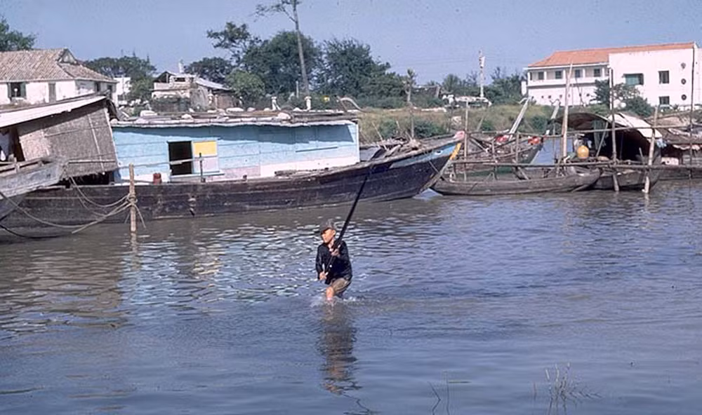 Cạu bé bắt cá trên sông.